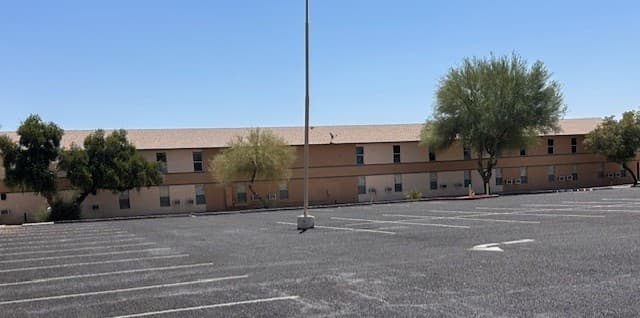 The two-story dorm building at Saddle Mountain RV Park, with trees along the front and a paved parking lot.